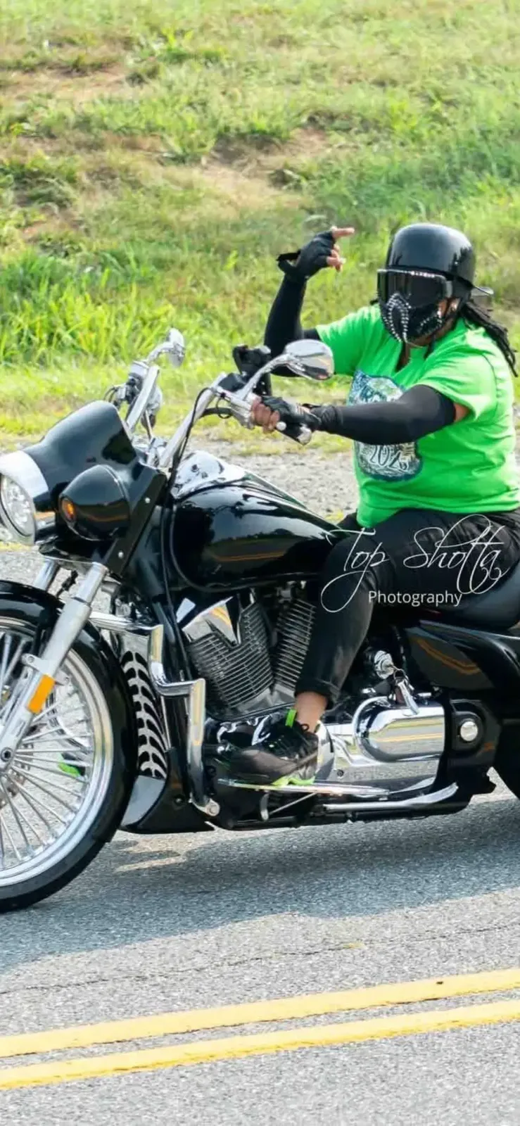 Motorcycle rider in a bright green shirt on a two-lane road