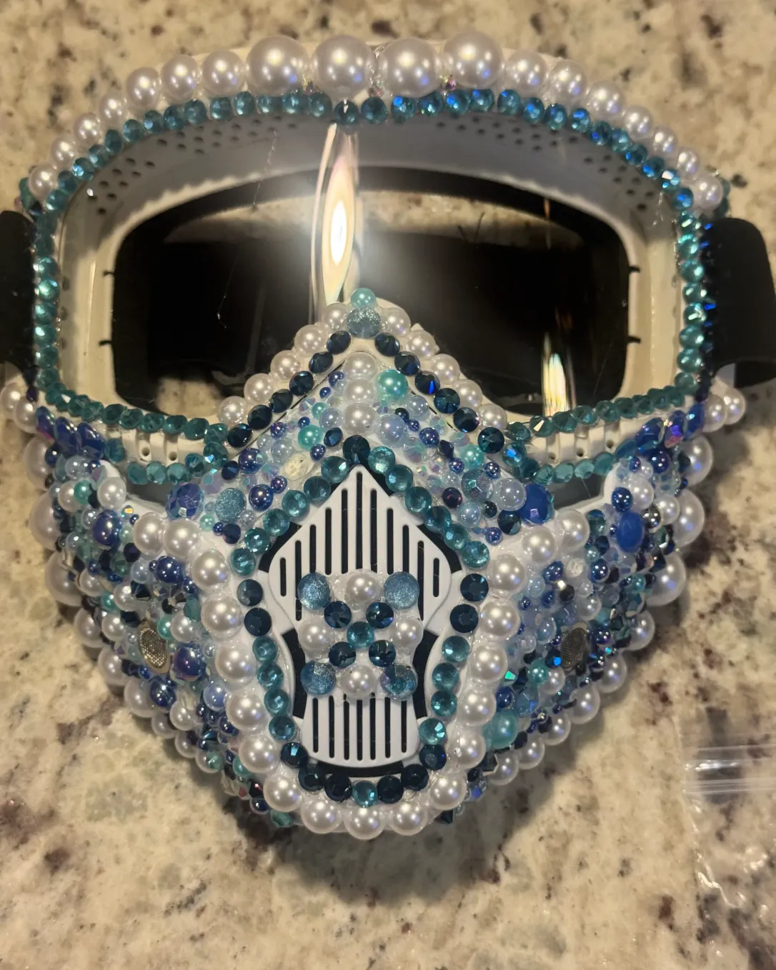 White spiked mask layered with white pearls, sky-blue crystals, and deep-blue crystals